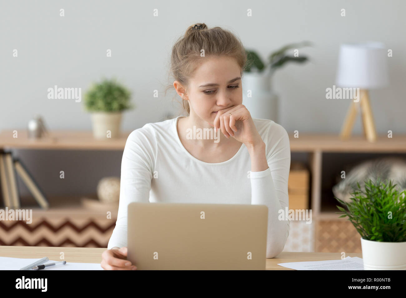 Junge nachdenkliche Frau am Schreibtisch sitzen Stockfoto