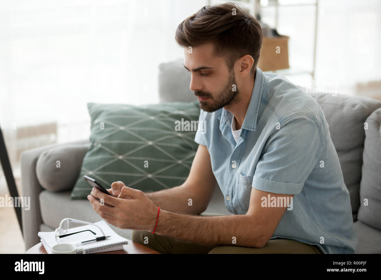 Ernster Mann holding Telefon Lesen einer Nachricht Stockfoto