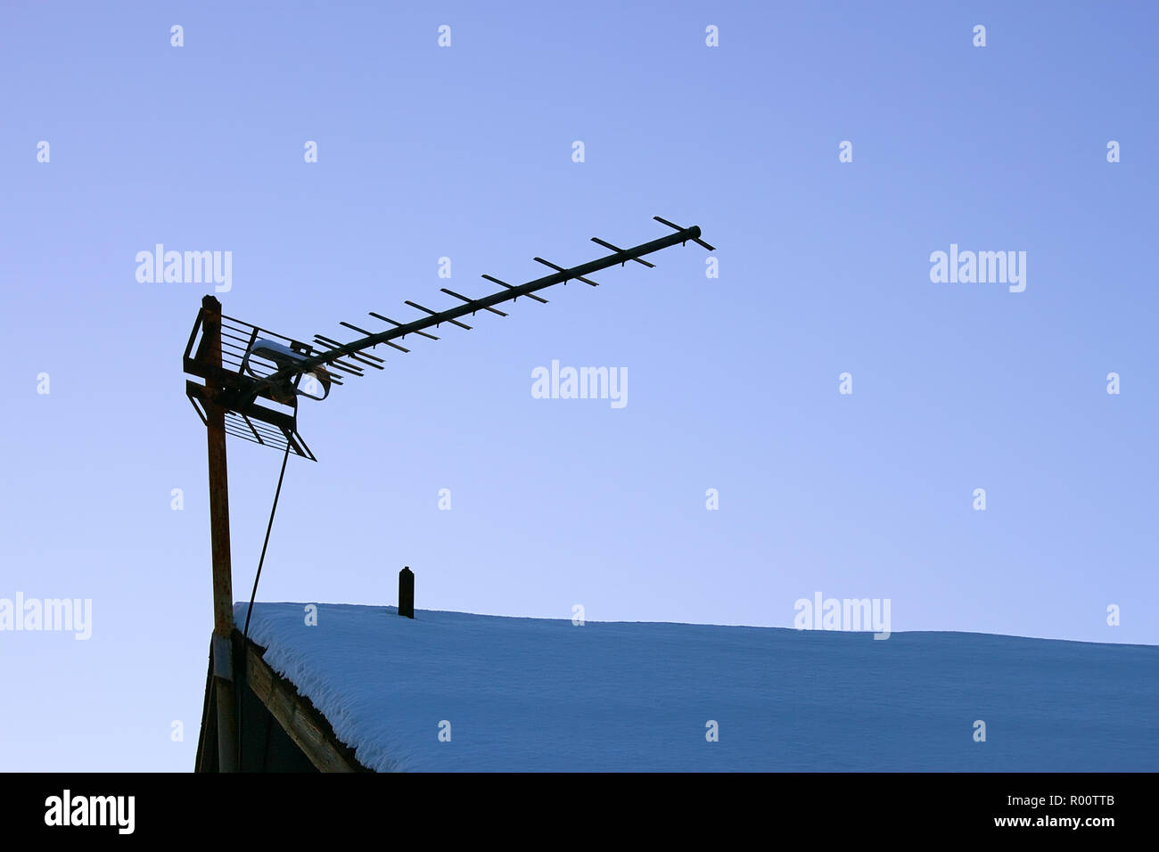 Die Fernsehantenne auf dem verschneiten Dach des alten Hauses Stockfoto