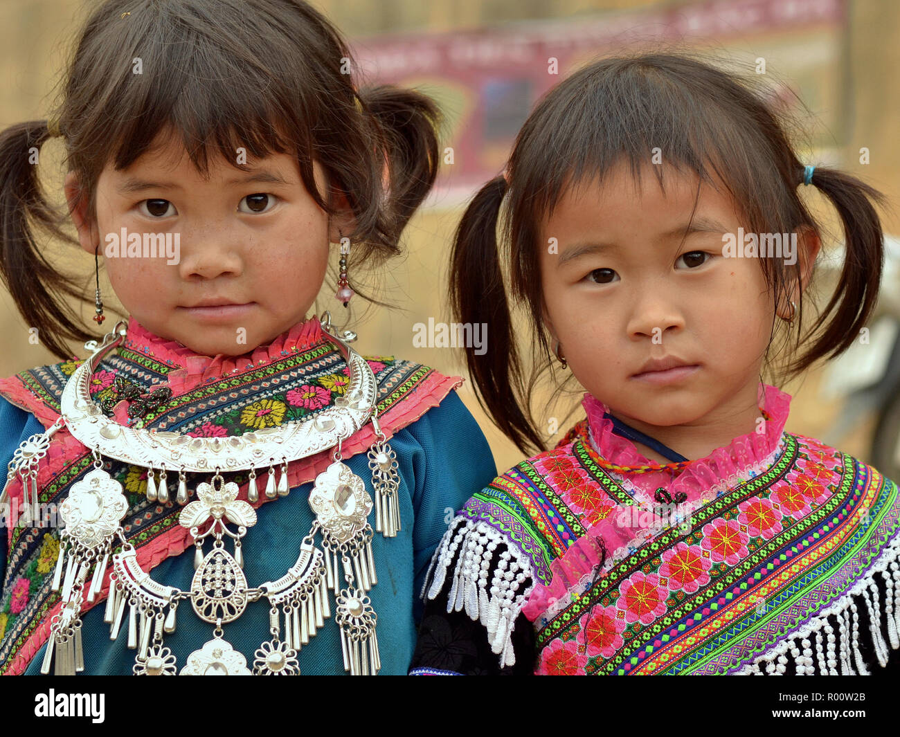 Zwei kleine vietnamesische Blume H'mong ethnische Minderheit Mädchen mit einem silbernen Halskette, gekleidet in farbenprächtige, bestickte traditionelle H'Mong Kleidung. Stockfoto