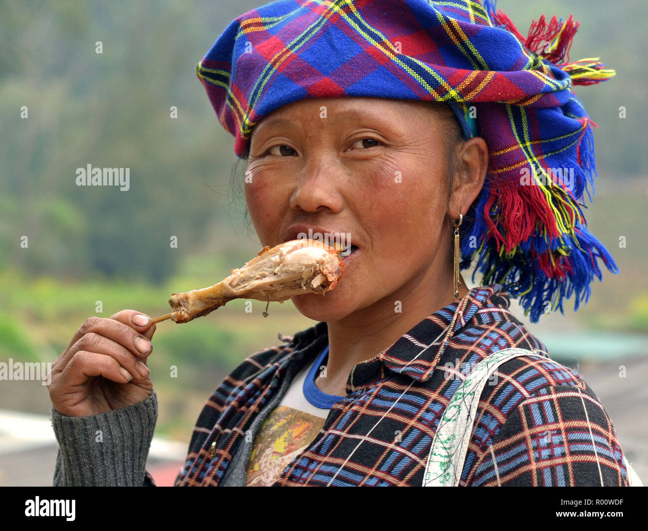 Vietnamesische ethnische Minderheit Bergvolk Frau mit Goldzahn isst ein Wok gebratenen Hähnchen drumstick. Stockfoto