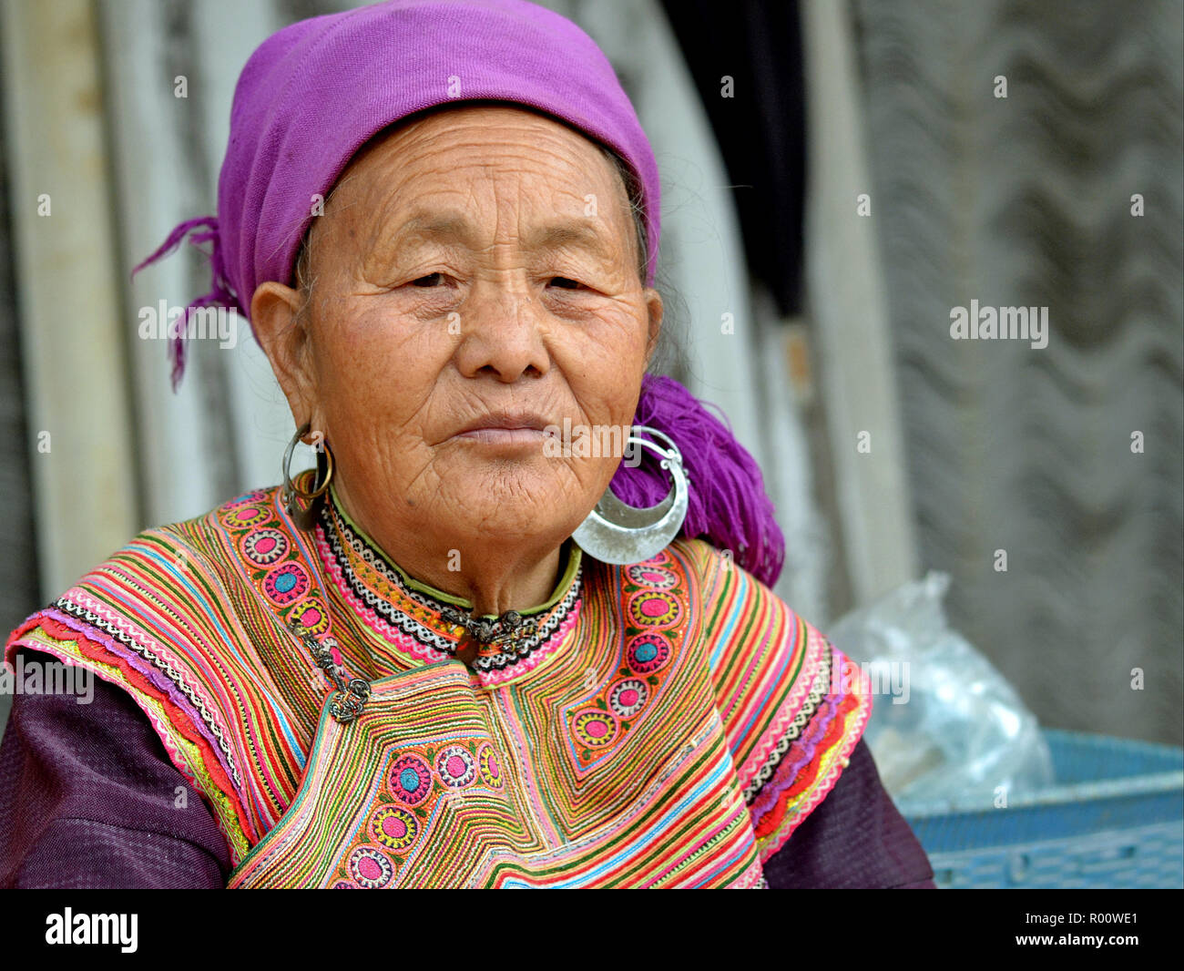 Ältere vietnamesischen Blume H'mong ethnische Minderheit Bergvolk Frau mit schweren tribal Silber Ohrringe und gestickte Blüte H'Mong Kleidung. Stockfoto
