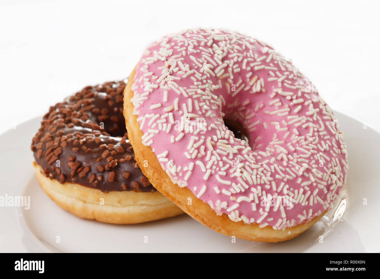 Rosa und Schokolade Donuts mit Streuseln auf einer Platte Stockfotografie -  Alamy