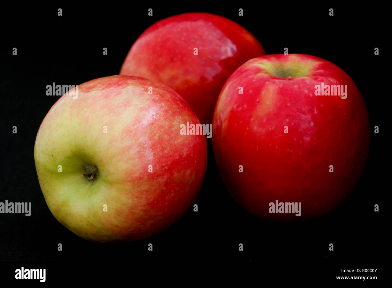 Drei pink lady Äpfel arrangiert auf Schwarz. Stockfoto