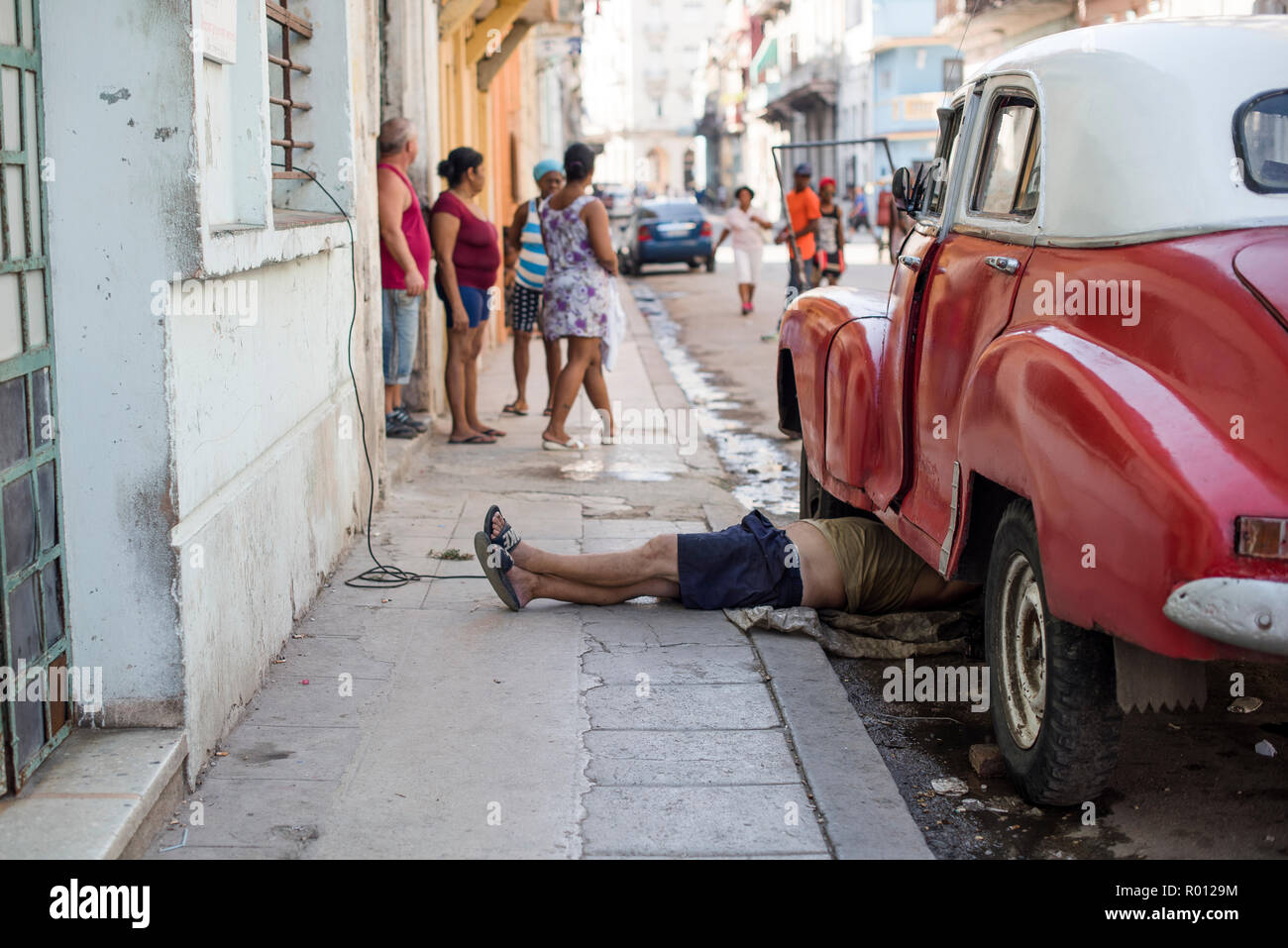 Ein Mann legt auf dem Bürgersteig sein Auto an einem heißen Tag in Havanna zu beheben. Stockfoto
