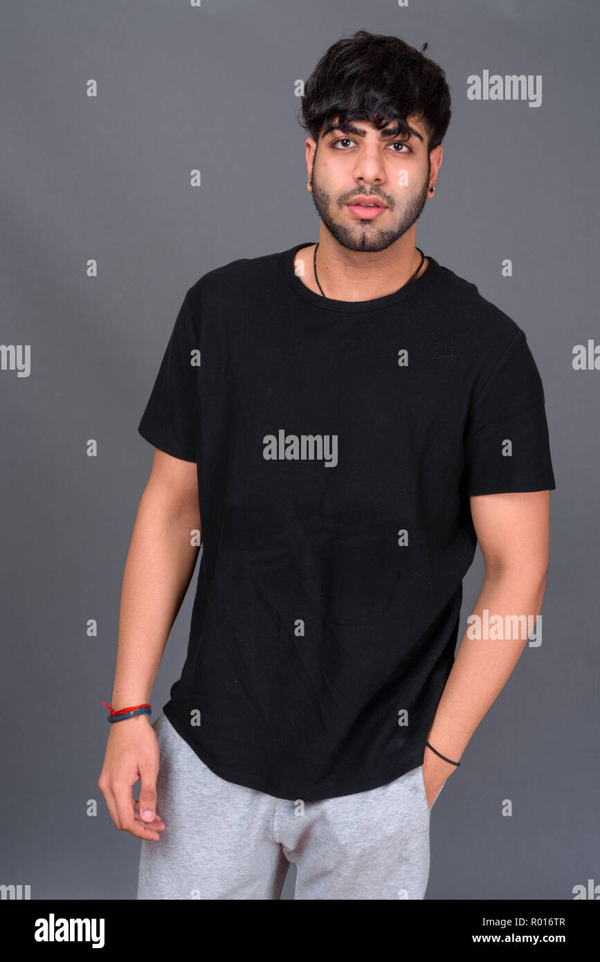 Junge schöne Indische Mann gegen grauer Hintergrund Stockfoto