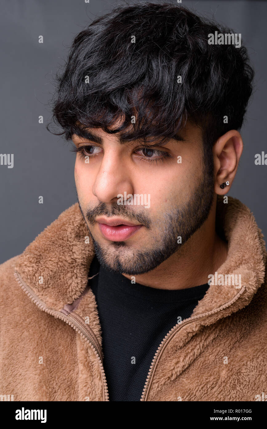 Junge schöne Indische Mann gegen grauer Hintergrund Stockfoto