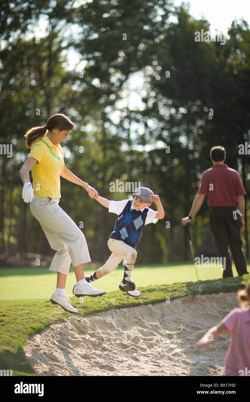 Junge ziehen seine Mitte - Erwachsene Mutter in einem Sandkasten auf einem Golfplatz. Stockfoto