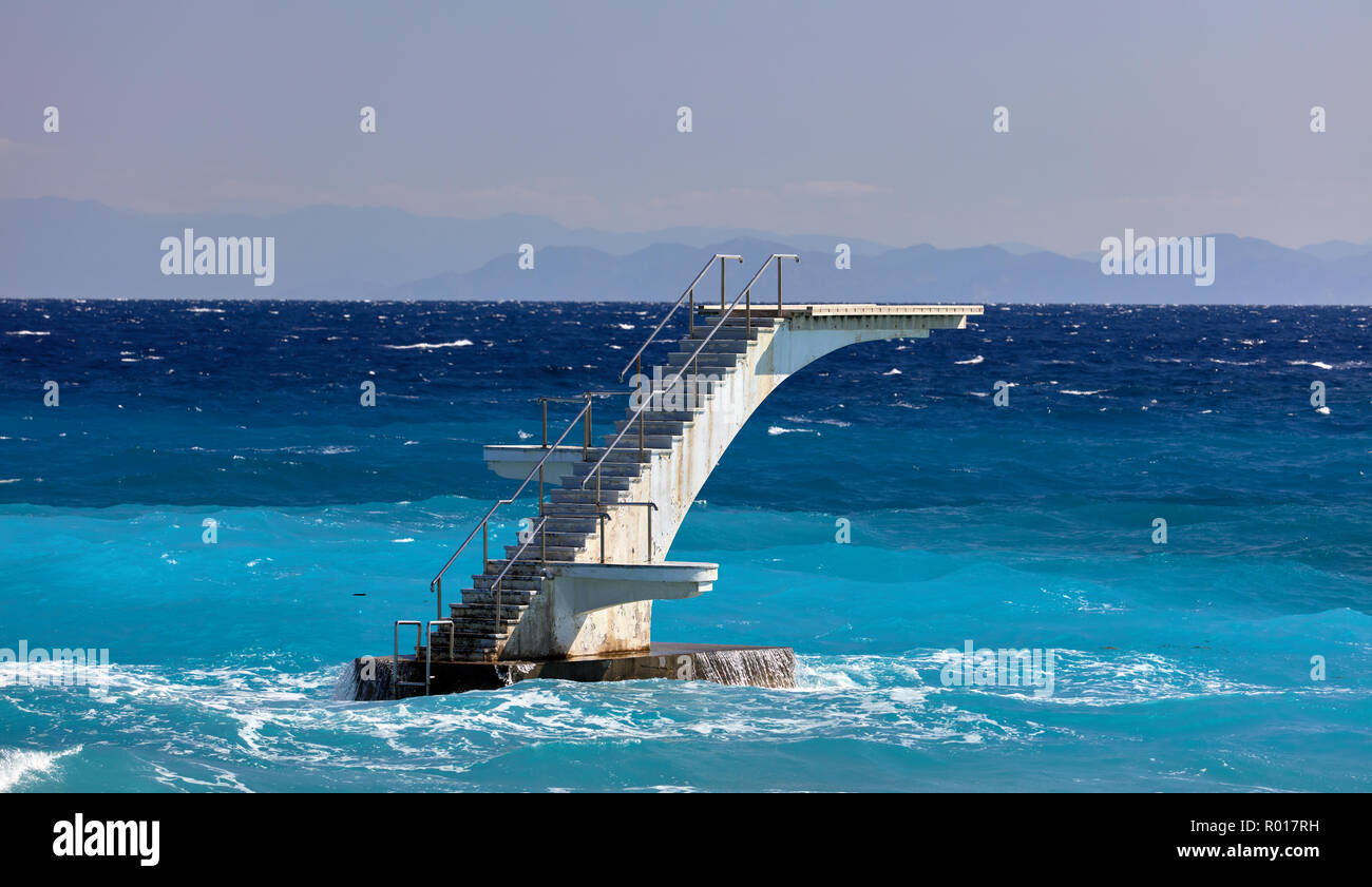 Sprungbrett von Wellen und einem strahlend blauen Meer in Rhodos, Griechenland umgeben Stockfoto