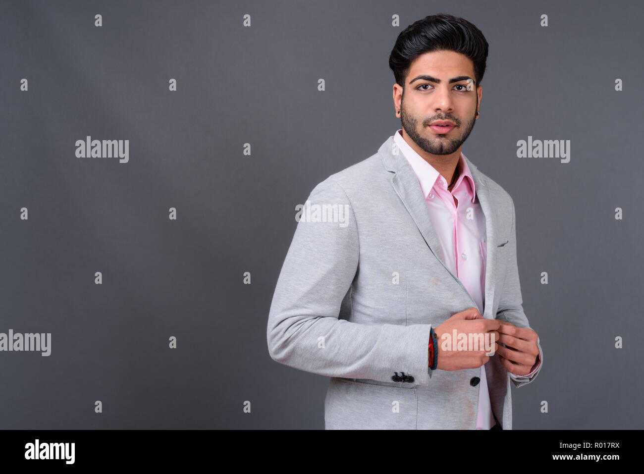 Junge hübscher indischer Geschäftsmann gegen grauer Hintergrund Stockfoto