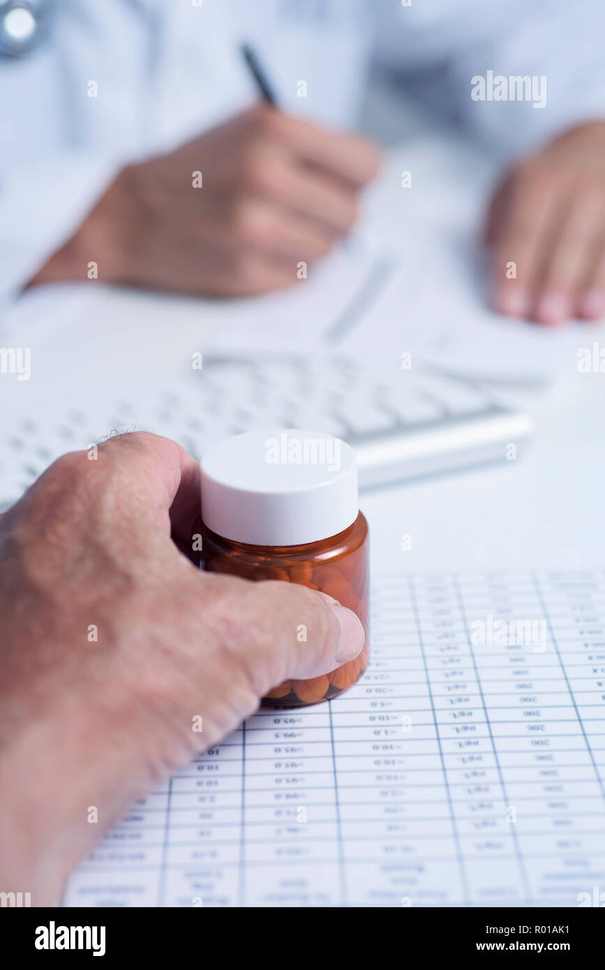 Nahaufnahme von einem kaukasischen Arzt Mann im weißen Kittel, die Unterzeichnung einer Verschreibung zu einem älteren kaukasischen Patienten Mann, habe eine Flasche Pillen in seiner Hand, s Stockfoto