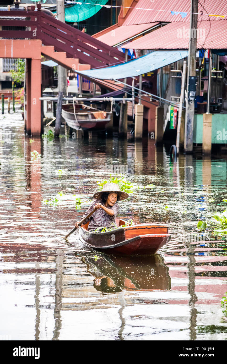 Damnoen Saduak, Thailand - 8. Oktober 2018: eine Frau Paddel ihr Boot am Kanal entlang. Der schwimmende Markt hier ist ein sehr beliebtes Touristenziel. Stockfoto