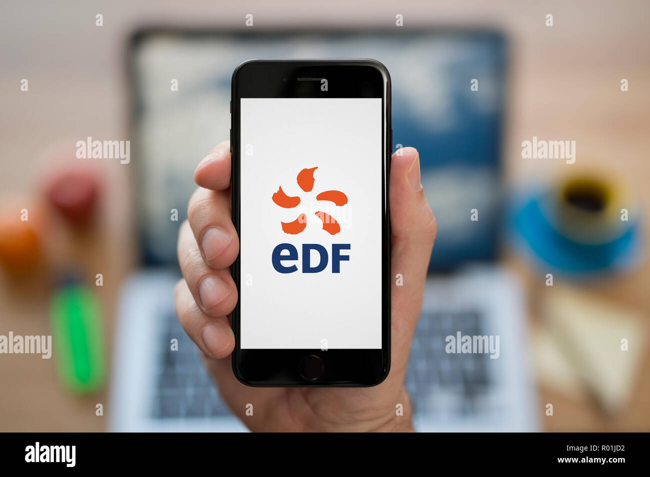 Ein Mann schaut auf seinem iPhone wird der EEF-Logo, während saß an seinem Computer Schreibtisch (nur redaktionelle Nutzung). Stockfoto