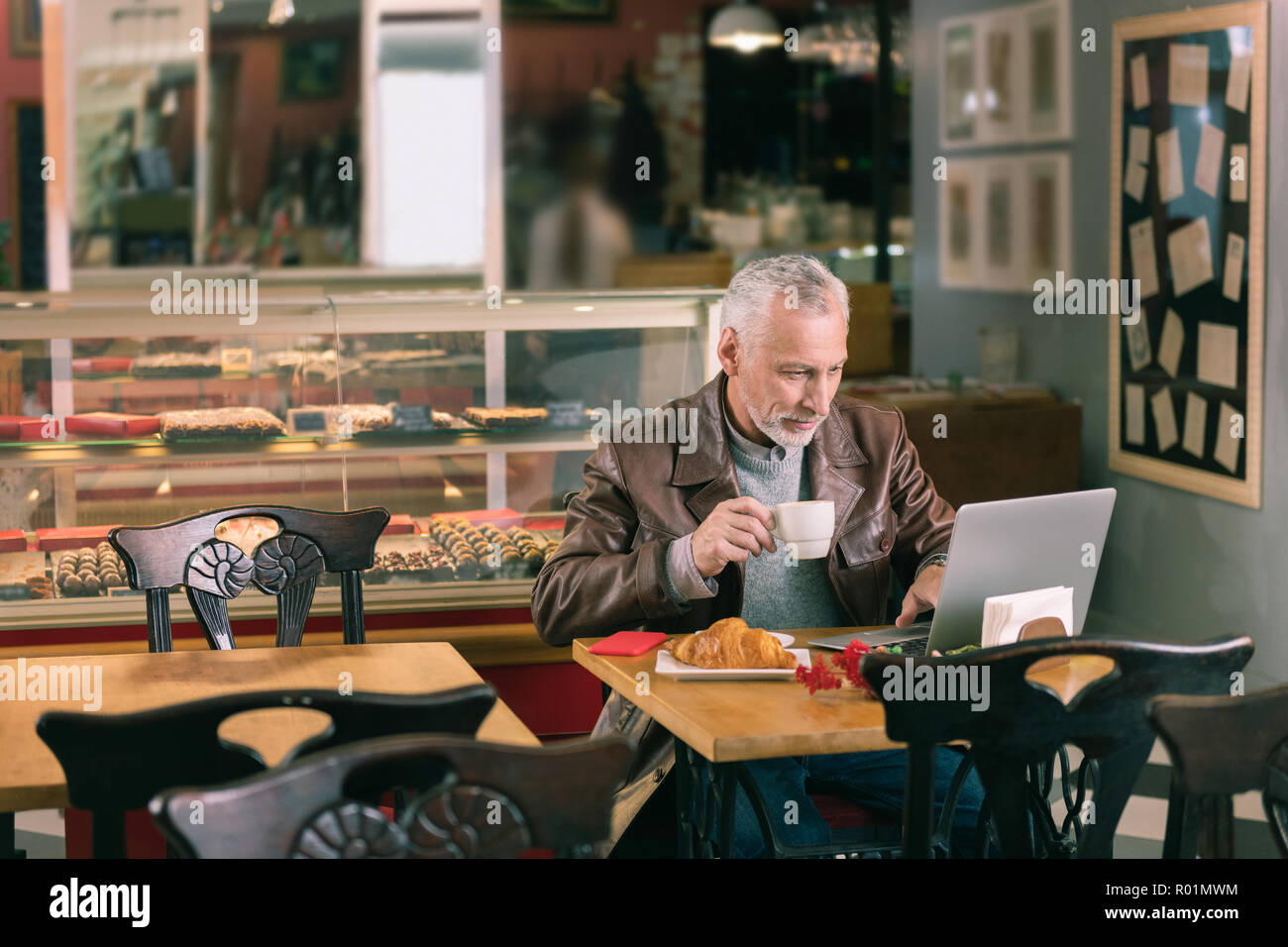 Berühmte Schriftsteller schreiben Roman mit seinem Laptop in Bäckerei sitzen Stockfoto