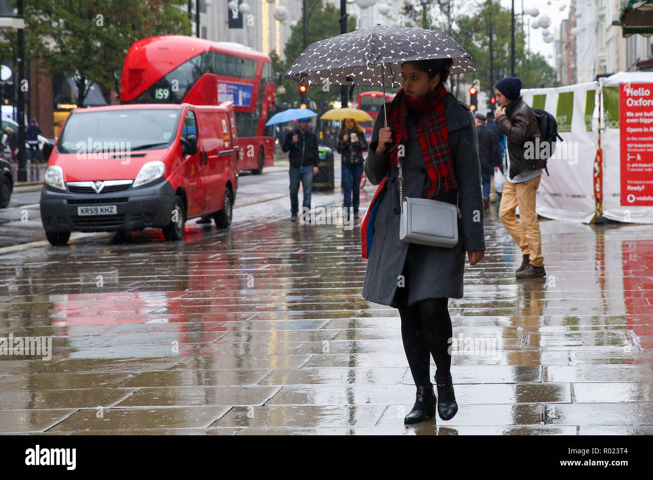 Die Oxford Street, London, UK. 1 Nov, 2018. Eine Frau, die Schutz vor dem Regen unter einem Dach als Regen fällt in London. Credit: Dinendra Haria/Alamy leben Nachrichten Stockfoto