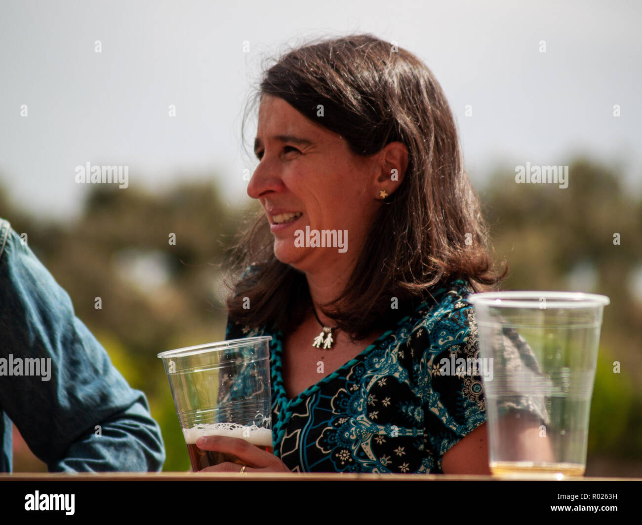 Eine Frau trinkt Bier bei einer Feier im Freien Stockfoto