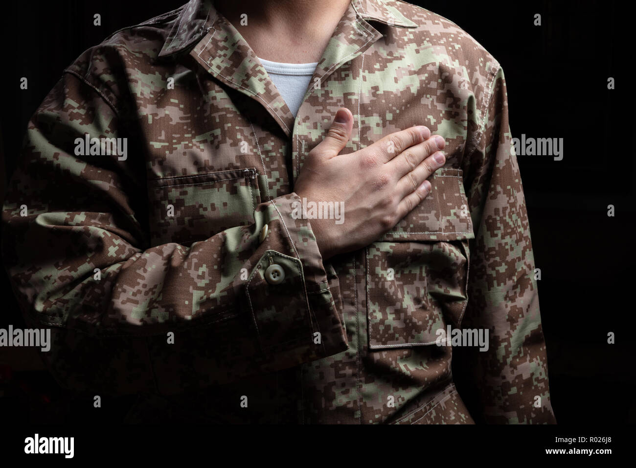 US-Armee. Junge Soldaten mit Hand auf Herz stehend auf schwarzem Hintergrund Stockfoto