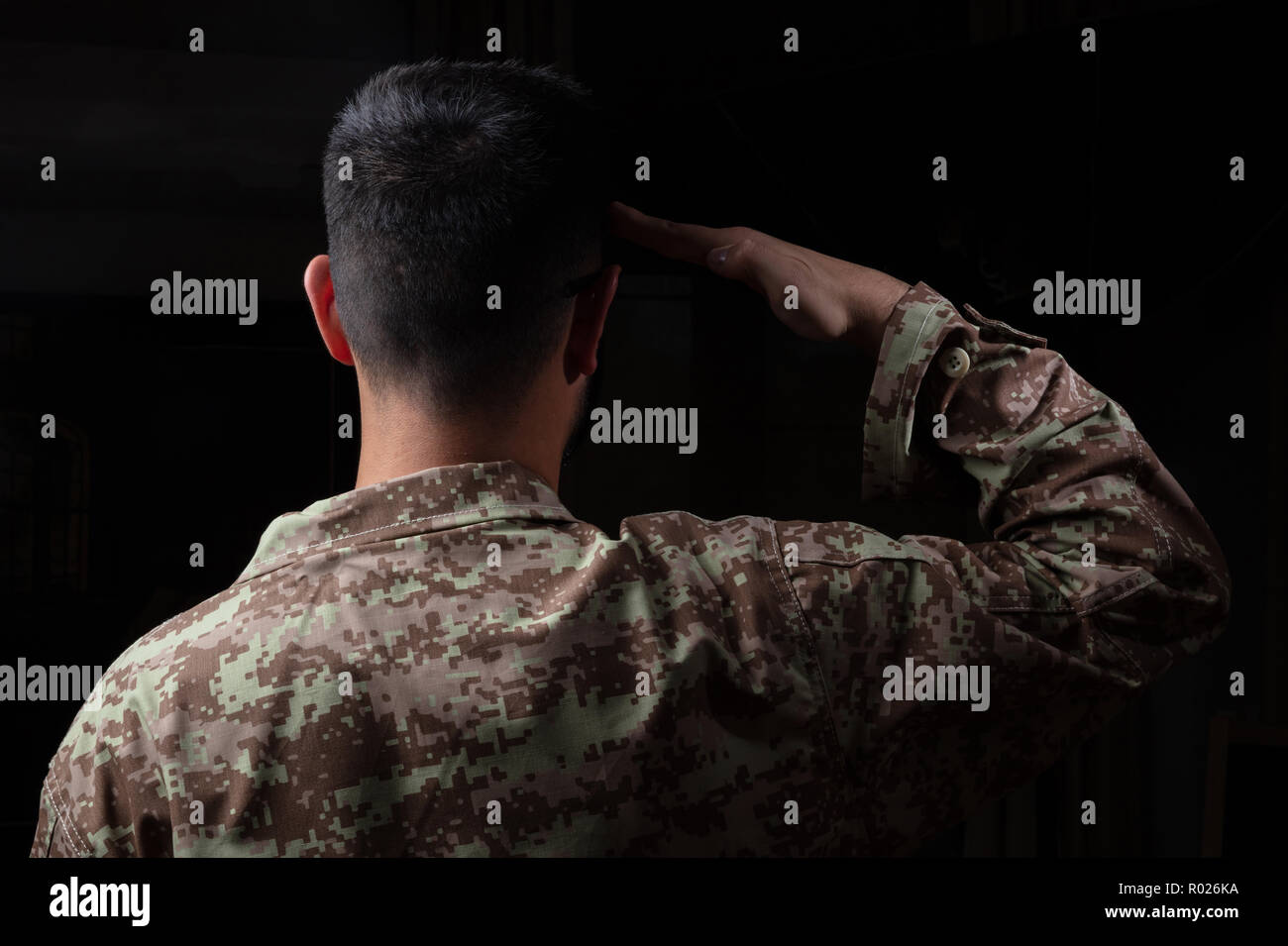 US-Armee. Junge Soldat salutierte stehend auf schwarzem Hintergrund Stockfoto