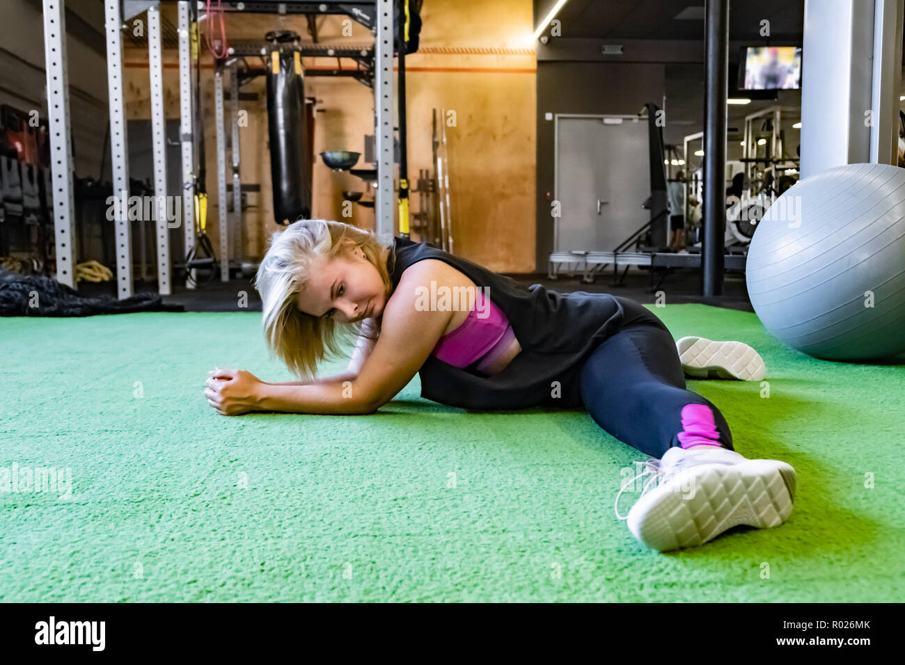 Junge passende Frau an der Turnhalle tun Split trainieren. Sportlerin im Fitnessraum trainieren Sie auf Seite 2 Stockfoto