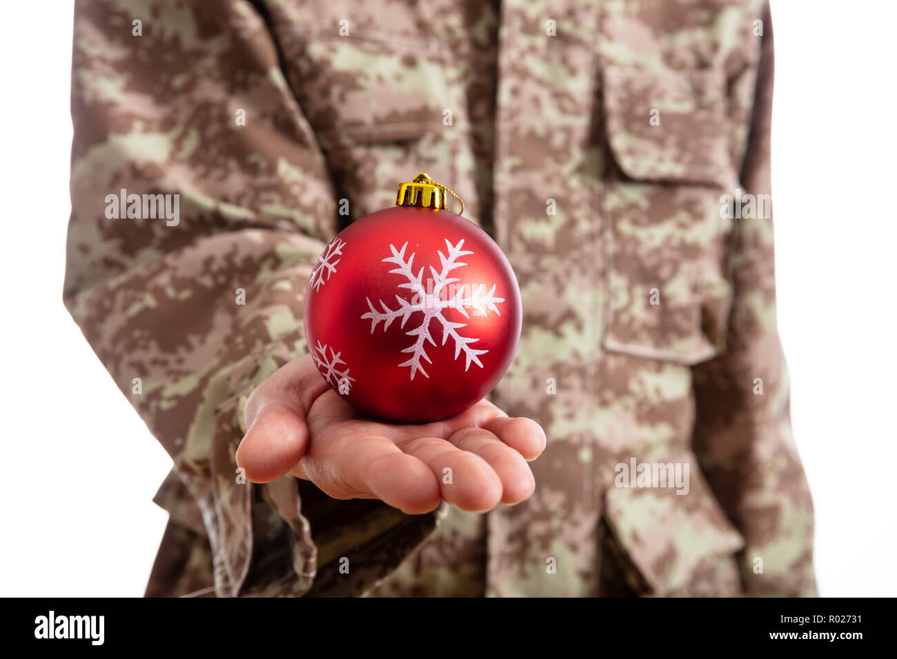 Weihnachten und Armee. Junge Soldat hält ein rotes christmas Ball stehend auf weißem Hintergrund Stockfoto