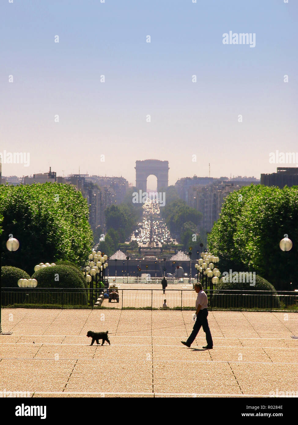 Ein Hund geht seinen Mann in der Axe historique von Esplanade du Général de Gaulle, La Défense, Paris. Blick auf den Triumphbogen und der Place de l'Étoile Stockfoto