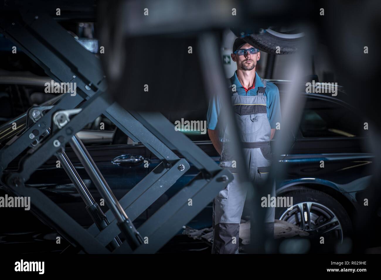 Kaukasische Automechaniker zwischen Fahrzeug auf eine Aufzüge. Moderne Fahrzeuge Wartung. Stockfoto