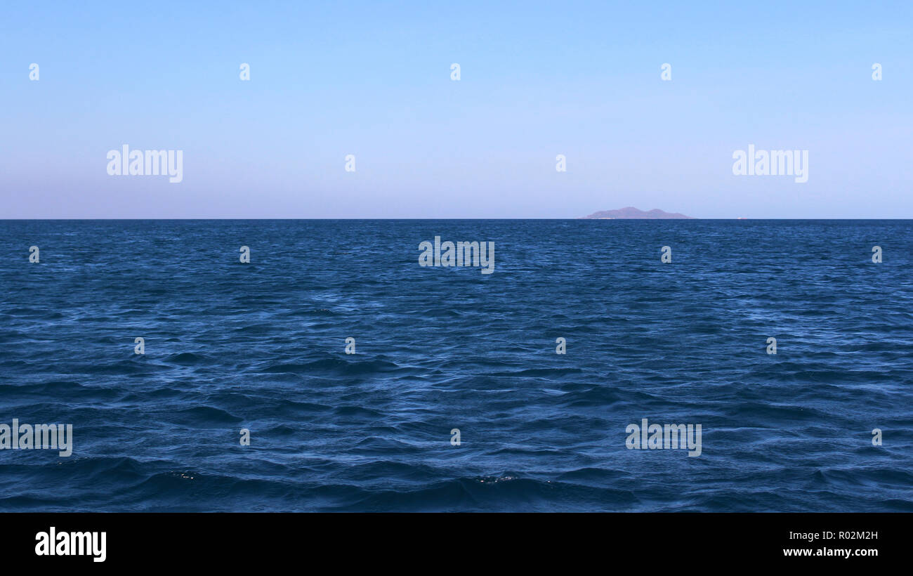 Die blauen Ozean mit einem Berg in der Ferne. Stockfoto