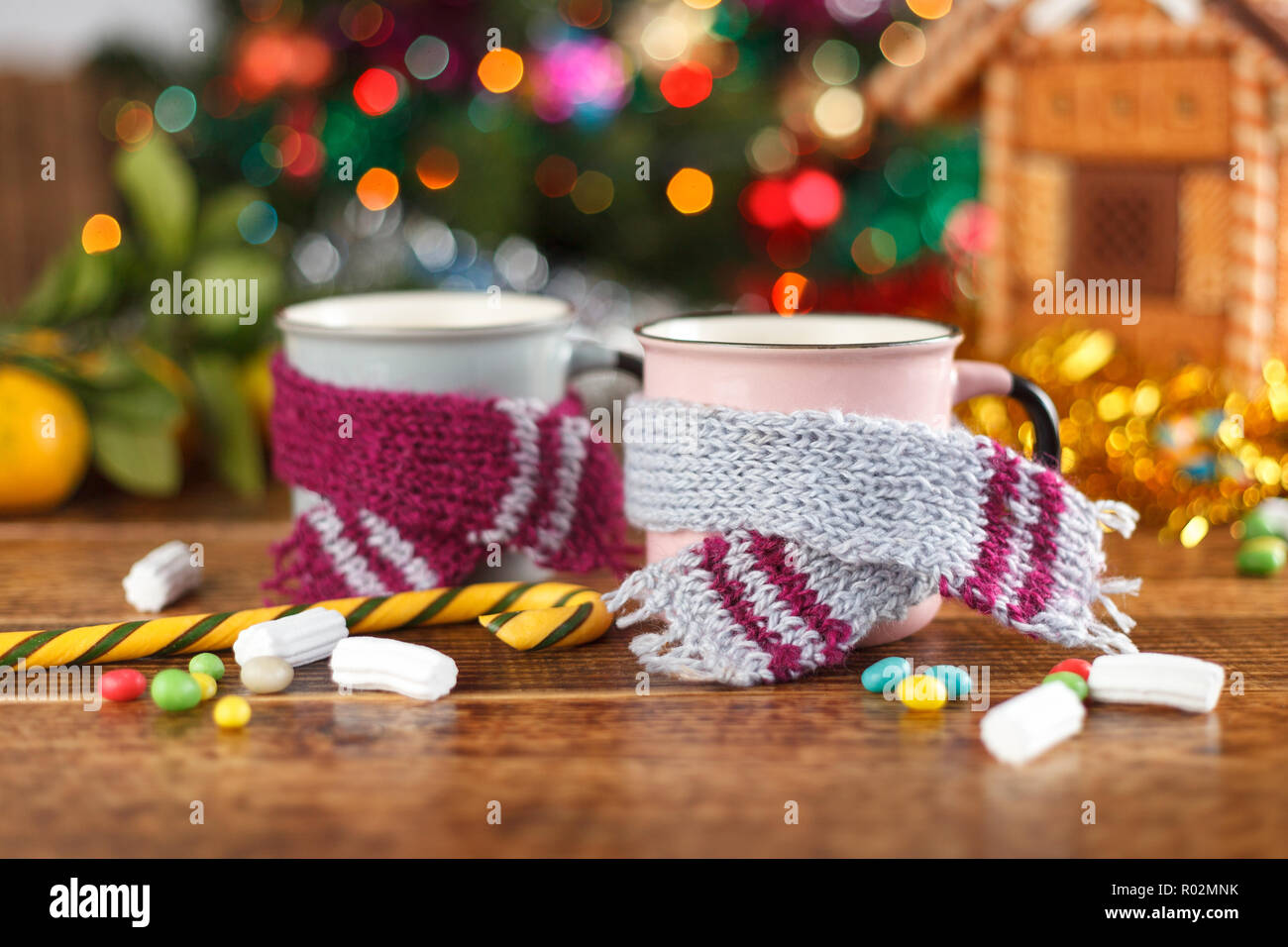 Tassen in der gemütlichen Schals auf dem Hintergrund einer Lebkuchenhaus. Das neue Jahr noch leben. Stockfoto