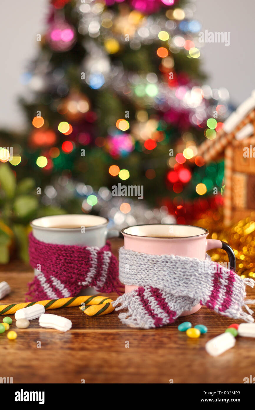 Tassen in der gemütlichen Schals auf dem Hintergrund der Weihnachtsbäume. Das neue Jahr noch leben. Stockfoto