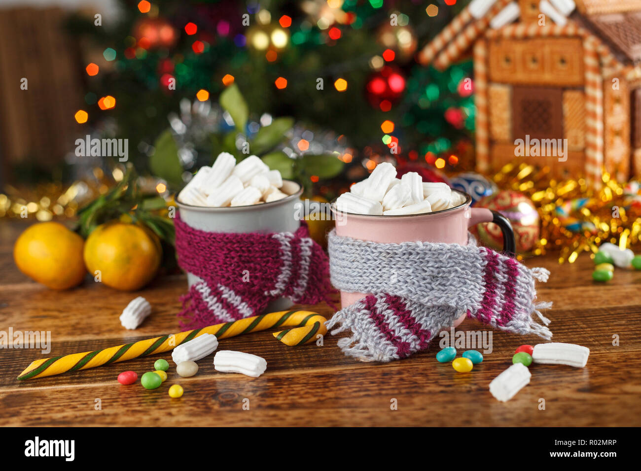 Becher in Schals mit einem heißen Getränk Marshmallows und Süßigkeiten. Festliche noch leben. Close-up. Stockfoto
