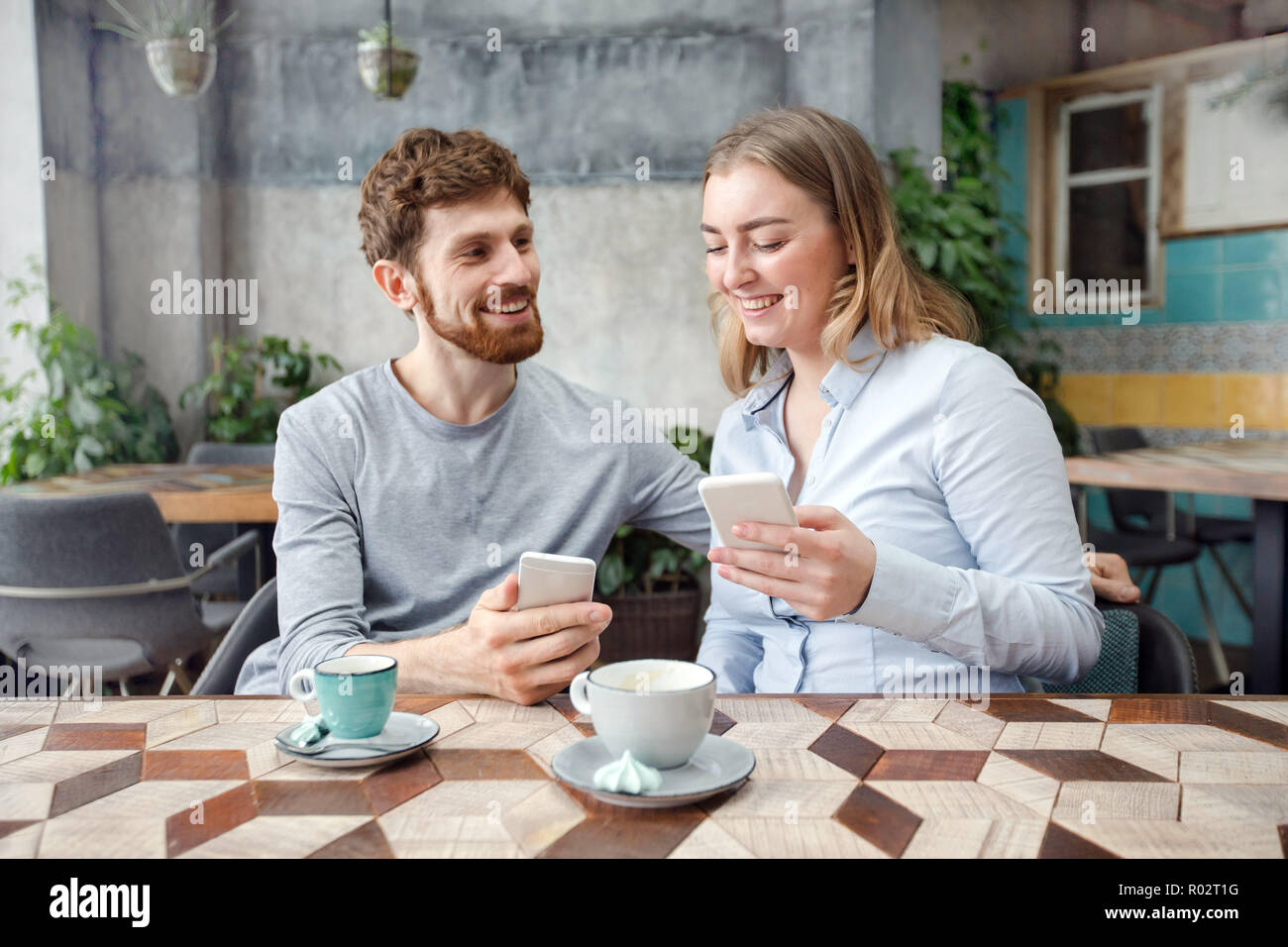 Freundliche Paar mit Kaffee und Telefon im Cafe Stockfoto
