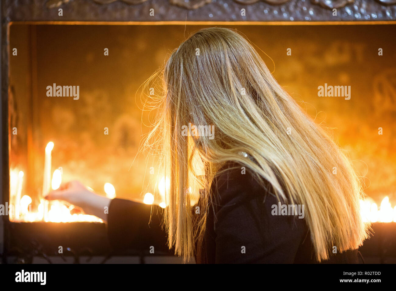 Mädchen mit blonden Haaren eine Kerze in der Kirche Stockfoto