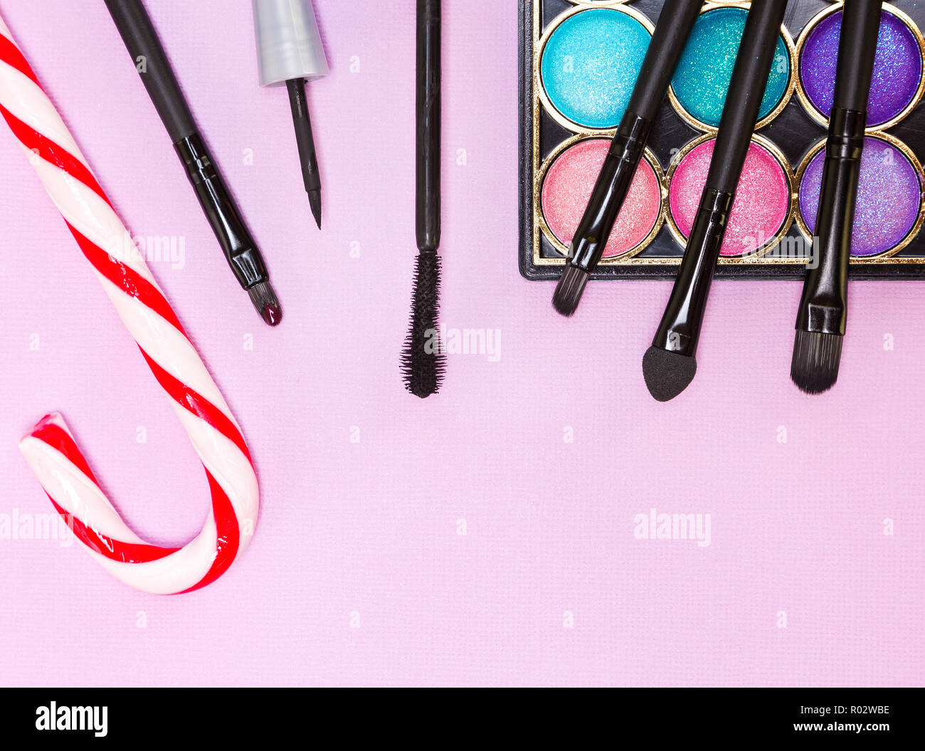 Weihnachten Make-up Kosmetik. Helle farbe Glitzer Lidschatten, schwarzer Eyeliner, Mascara, Lipgloss, Make up Pinsel und Applikator mit Zuckerstange auf Stockfoto