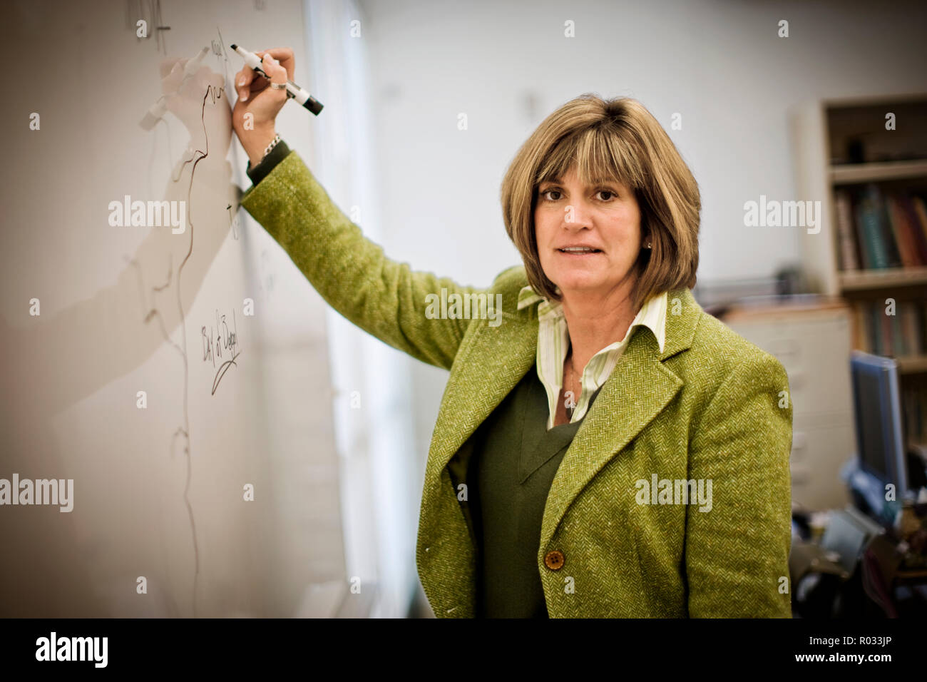 Porträt einer Mitte - Erwachsene Lehrerin Schreiben in eine Tafel in einer Schule. Stockfoto