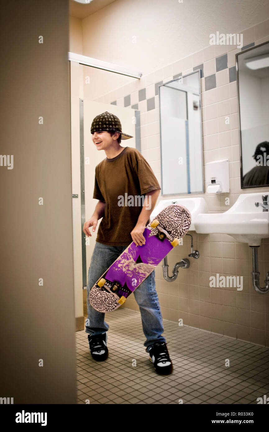Teenager mit einem Skateboard in eine Toilette. Stockfoto