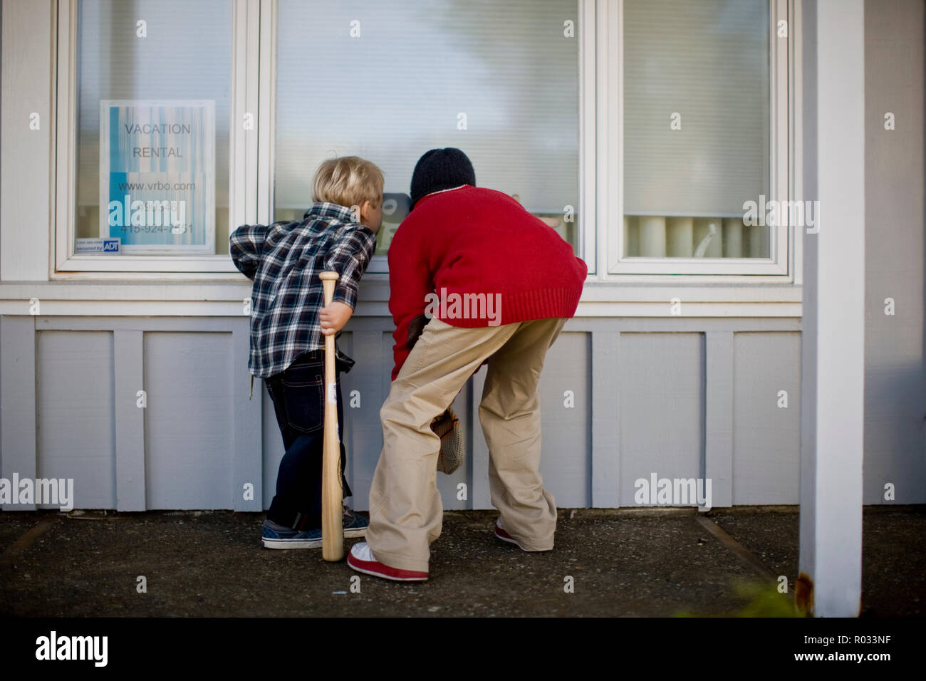 Zwei Jungen blickend in Fenster von einem leeren Haus Stockfoto