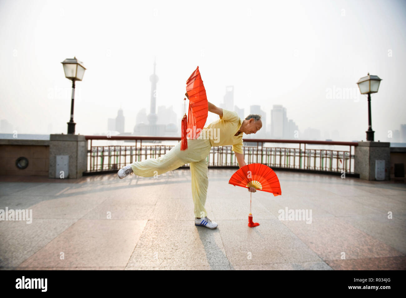 Reife Männer üben von Tai Chi, während Sie einen dekorativen Ventilator in der Stadt. Stockfoto