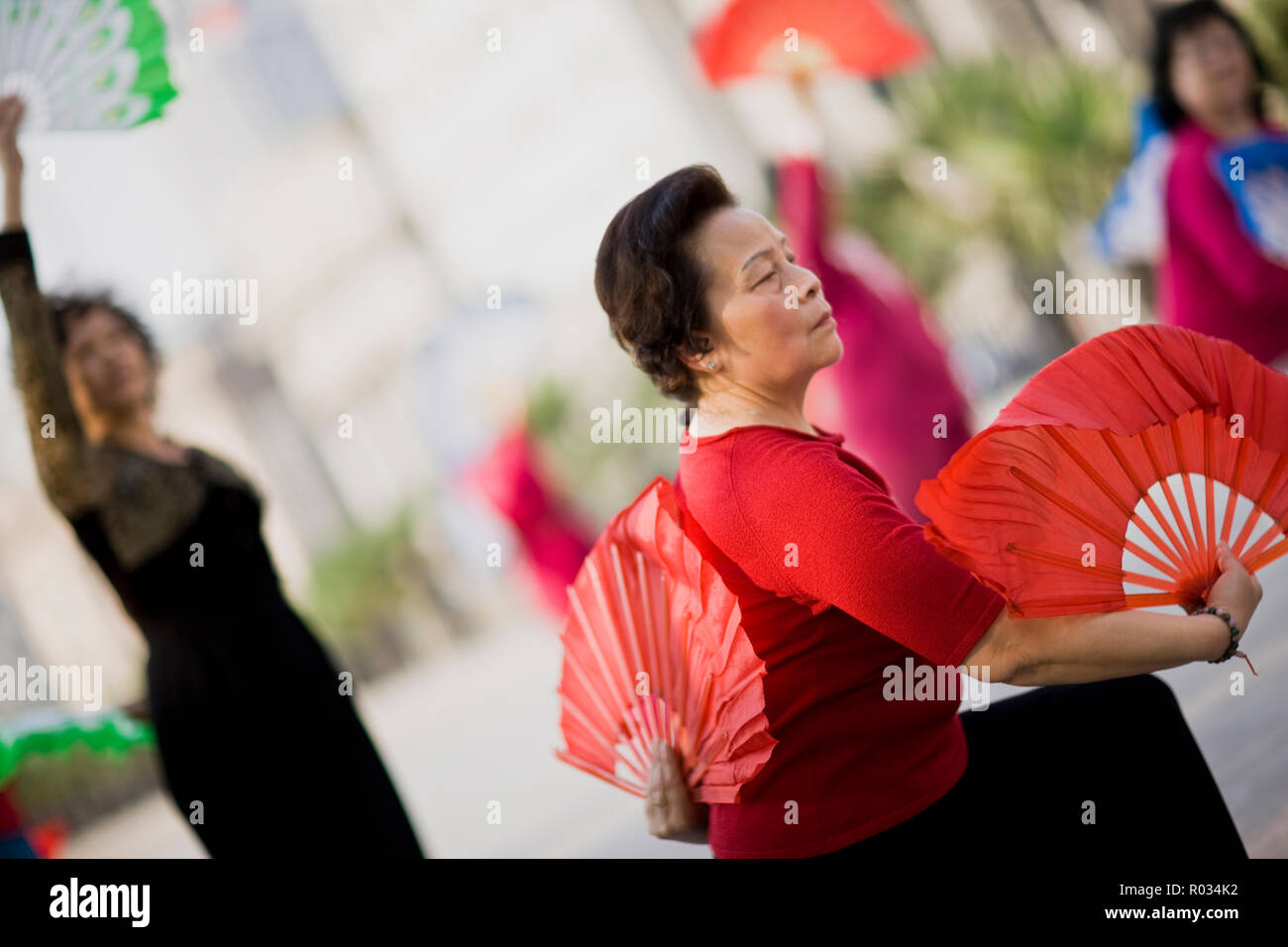 Traditionelle Tänzer rote Zier Lüfter beim Tanzen im Freien. Stockfoto