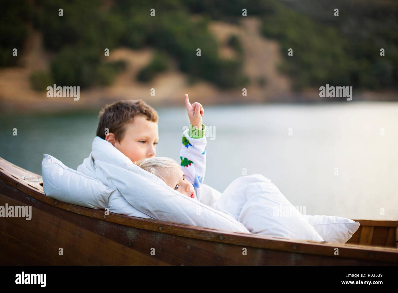 Junge und sein junger Bruder in eine Wolldecke eingewickelt, während im Innern ein hölzernes Boot sitzen. Stockfoto