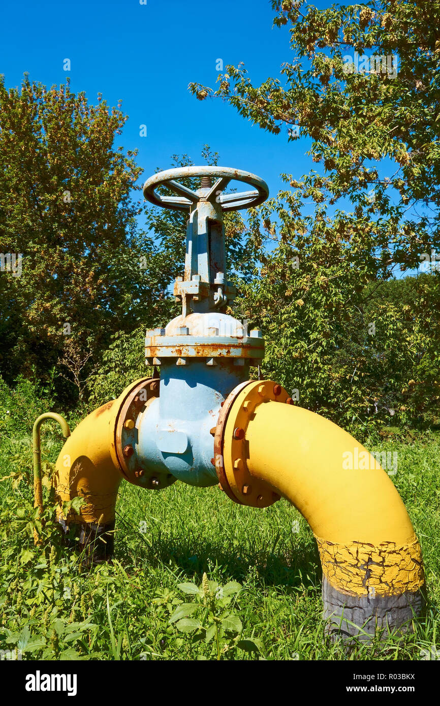 Große gebogene Metall Gasleitung mit einem Ventil auf grünem Rasen Stockfoto