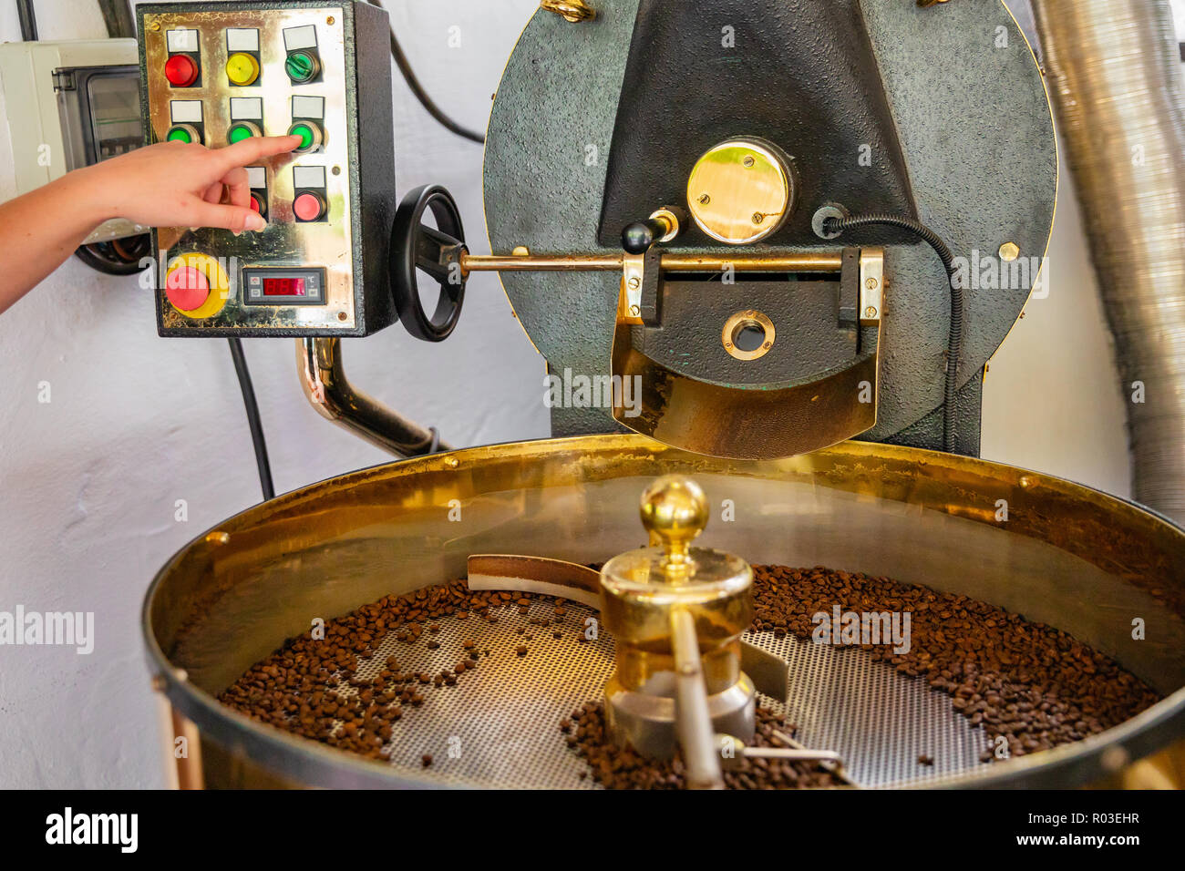 Weibliche Mitarbeiter Maschinen drücken Taste auf Kaffeeröster Stockfoto