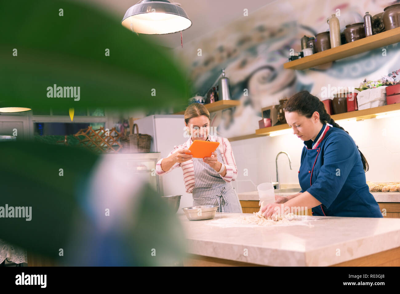 Strahlende Unternehmer machen Video ihres Mitarbeiters kochen Croissants Stockfoto