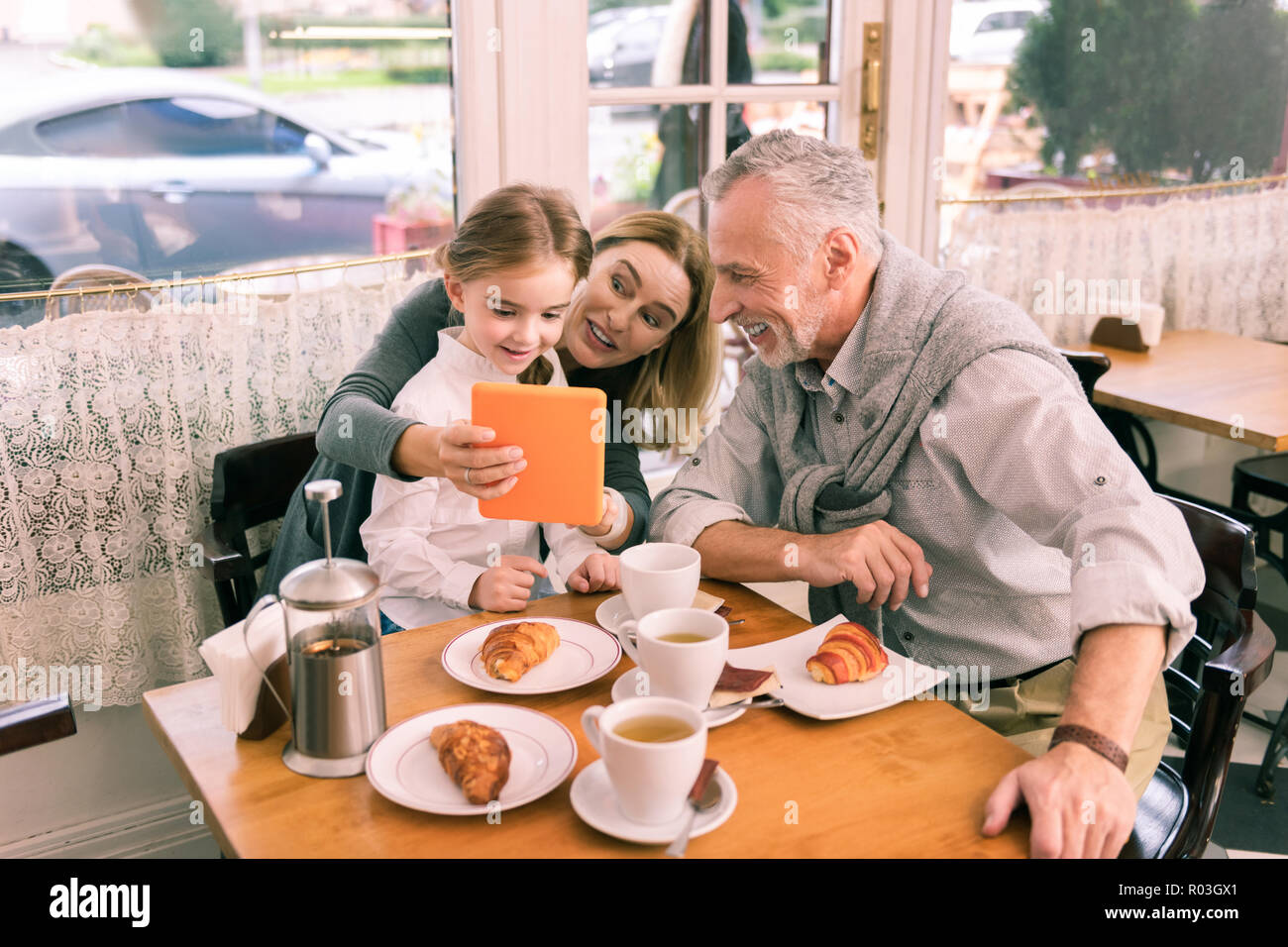 Paar Großeltern Holding orange Tablet beim Spielen mit ihren Mädchen Stockfoto