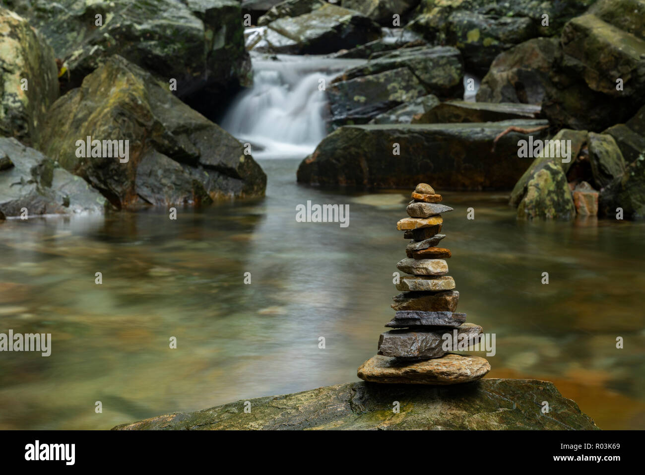 Verschiedene geformte Zen Steine gegen einen Wasserfall Hintergrund gestapelt Stockfoto
