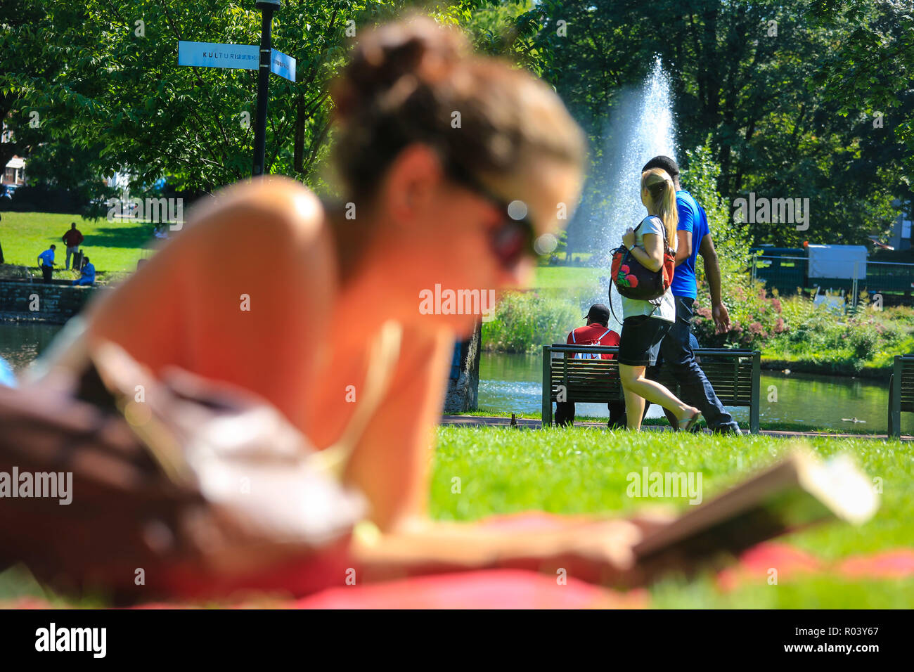 Essen, Deutschland, Ruhrgebiet, City Garden, junge Frau liegt auf der Wiese und liest in einem Buch Stockfoto