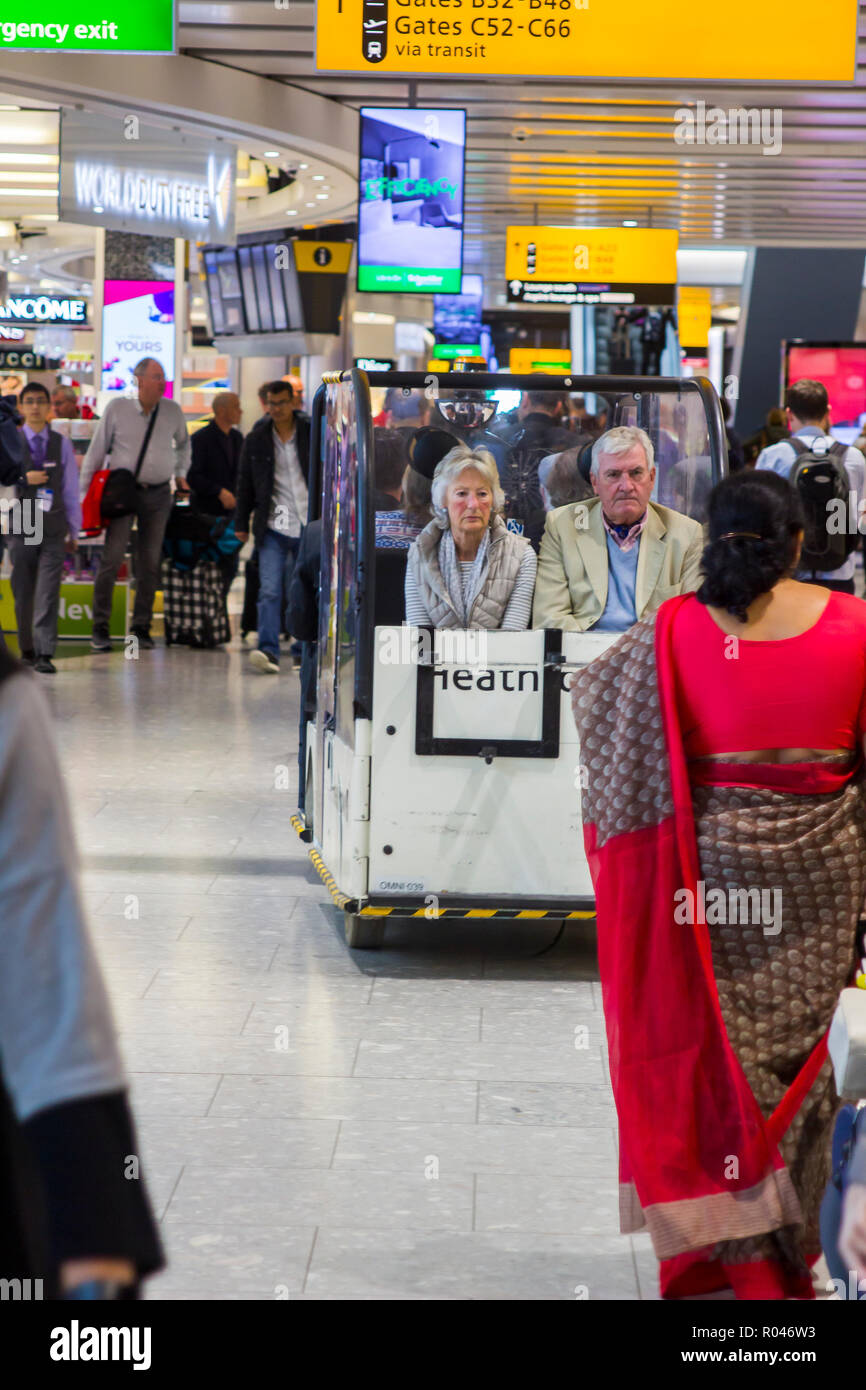 2. Mai 2018 ein Paar müde, die Passagiere in einem kleinen Menschen Träger im Terminal 2 Heathrow Airport London England. Stockfoto