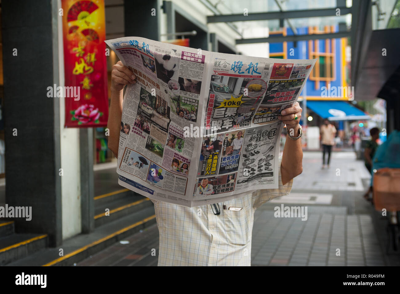 Republik Singapur, Mann liest Zeitung in Chinatown Stockfoto