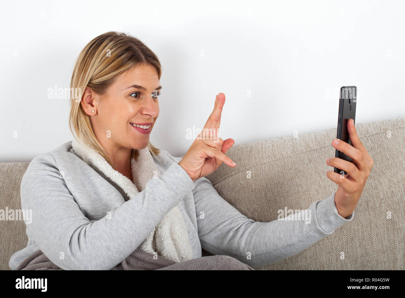 Gerne blonde Frau mit Facetime ihre Finger zeigen zu Freund Stockfoto