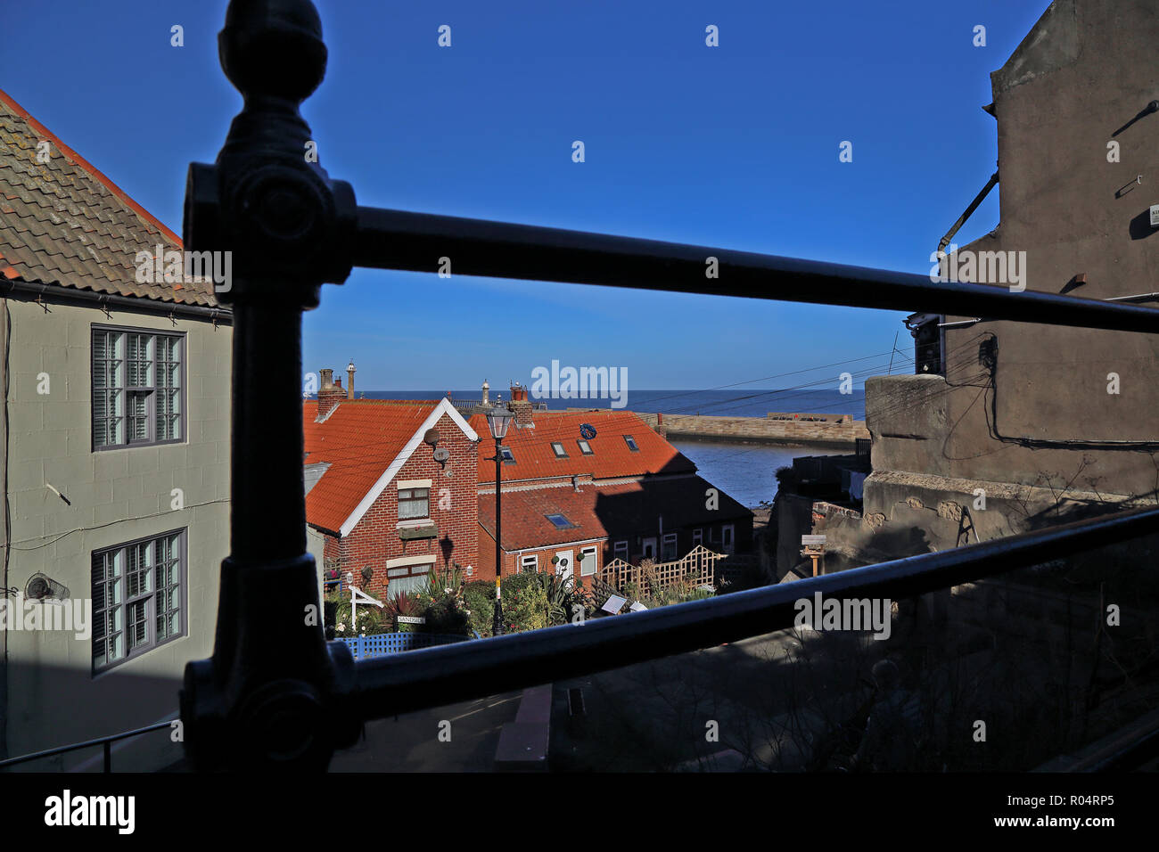 Eine Ansicht von Whitby und den Hafen durch Geländer von Church Lane an der Unterseite der St. Mary's Schritte an einem strahlenden Herbsttag mit blauen wolkenlosen Himmel. Stockfoto