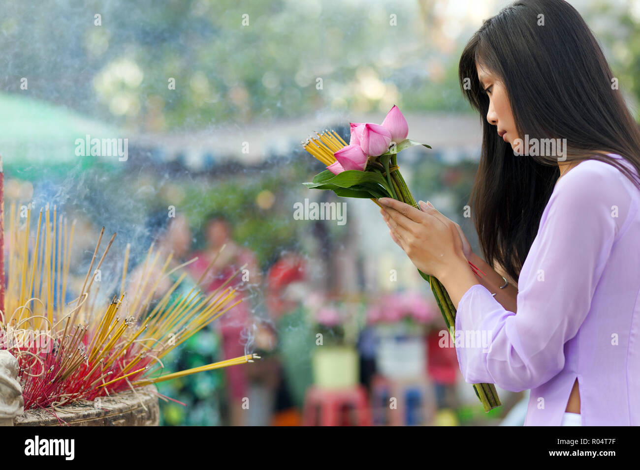 Cute vietnamesischen Mädchen beten im Freien an einem Tempel, bietet Lotus Blumen und Räucherstäbchen Stockfoto